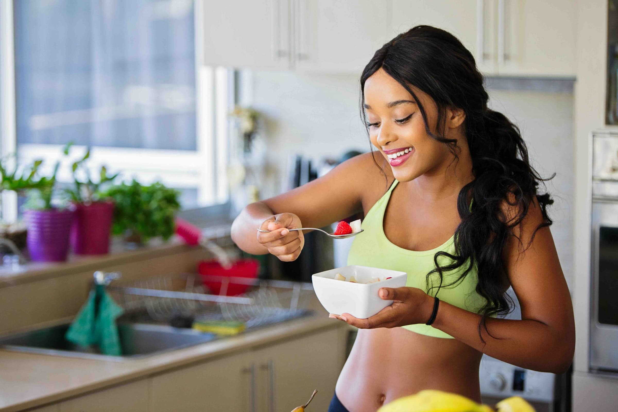 A woman eating a fresh fruit bowl at home